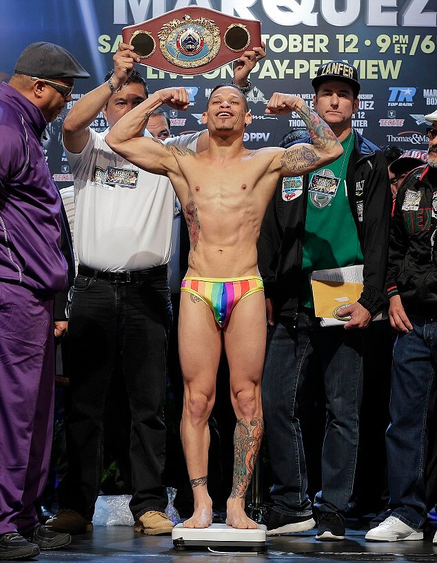 Orlando Cruz poses for photos while standing on the scale during the weigh-in for the WBO featherweight title fight against Orlando Salido, Friday, Oct. 11, 2013, in Las Vegas. Cruz, boxing's first openly gay fighter, will take on Salido in the 12-round title fight on Saturday. (AP Photo/Julie Jacobson)
