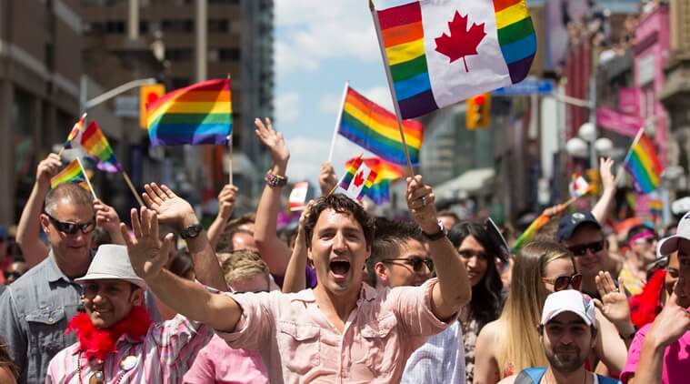 Prime Minister Justin Trudeau waves a flag as he takes part in the annual Pride Parade in Toronto on Sunday, July 3, 2016. (Mark Blinch/The Canadian Press via AP)