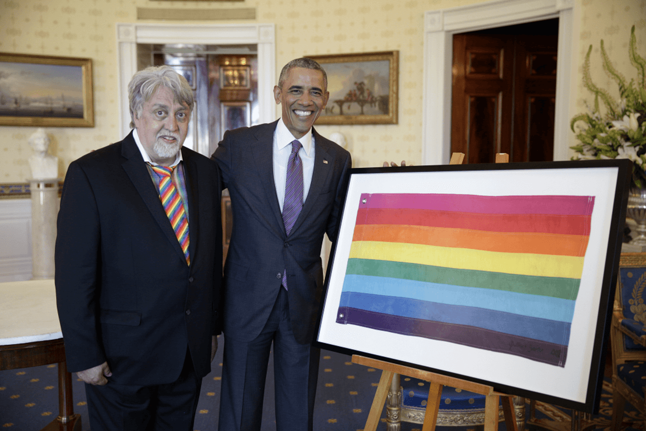 Il presidente Barack Obama osserva la bandiera del Gay Pride insieme a Gilbert Baker, l'artista che ha disegnato la bandiera, prima di una ricezione in riconoscimento del Mese dell'Orgoglio LGBT, nella Sala Blu della Casa Bianca, il 9 giugno 2016.